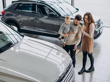 Eine Familie erkundet bei Autoankauf Köln und bewundert ein weißes Fahrzeug, während ein stilvoller SUV im Hintergrund in einem modernen Showroom zu sehen ist.